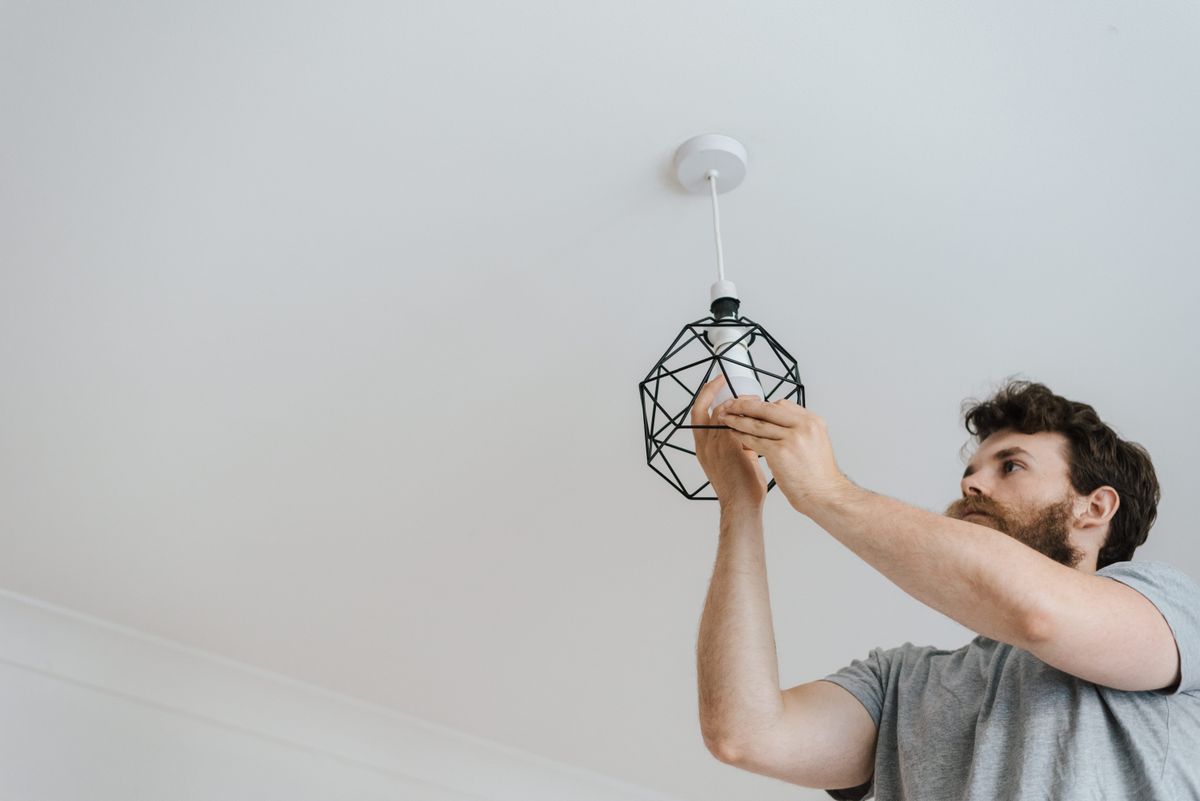 Technician installing an LED tube in an office ceiling